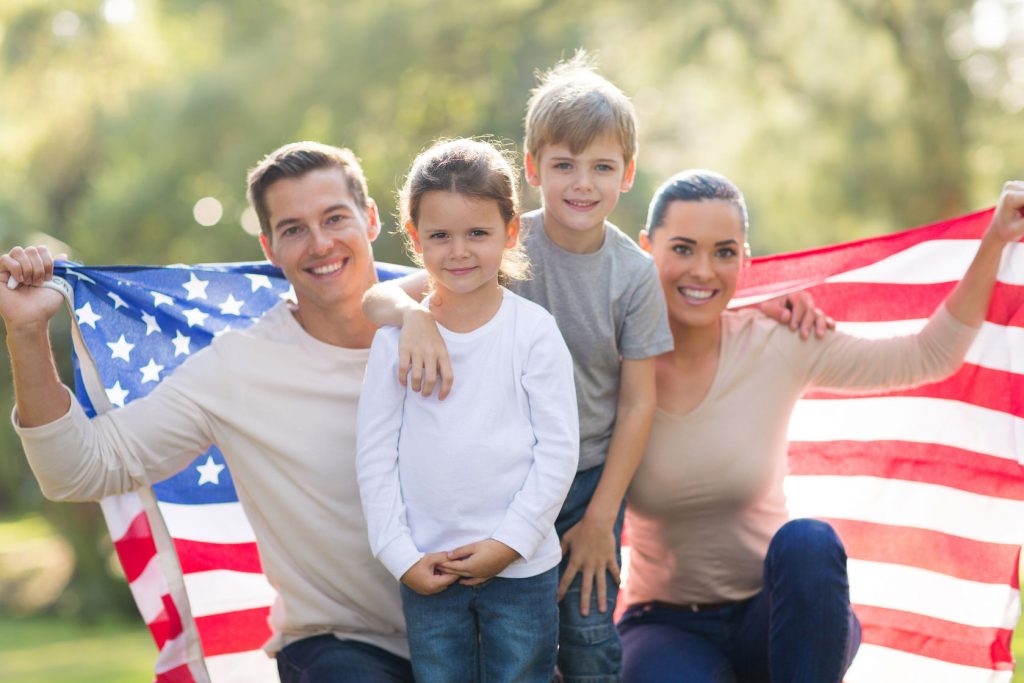 28819279 - portrait of beautiful modern american family with usa flag outdoors