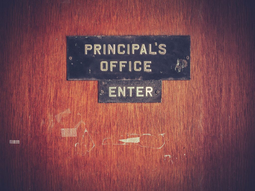 31583756 - retro filtered image of a grungy principal's office door at a public school in the usa