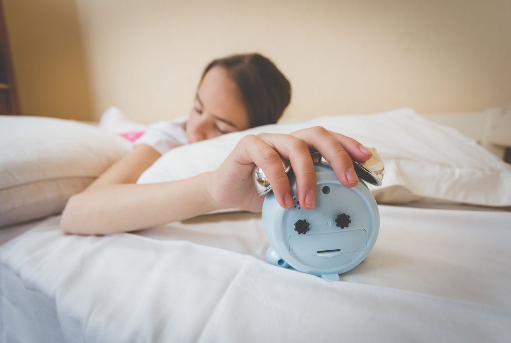 62442256 - closeup photo of young woman turning off alarm clock